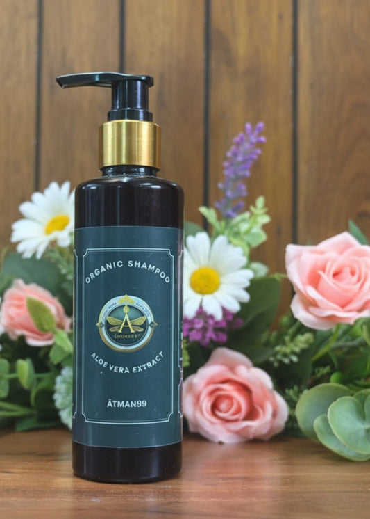 Black shampoo bottle with pump on a wooden surface and flower
 background

